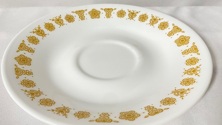 A closeup of a Butterfly Gold Corelle dish, a white plate with a pattern of gold flowers and butterflies around the edge