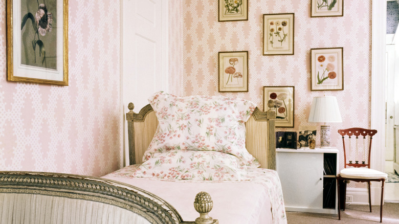 1970s bedroom with pink wallpaper and gallery wall of botanical prints surrounding bed with floral pillowcases