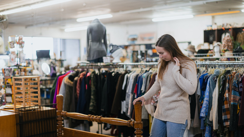 A woman looking down at something exciting on the floor of a thrift store.