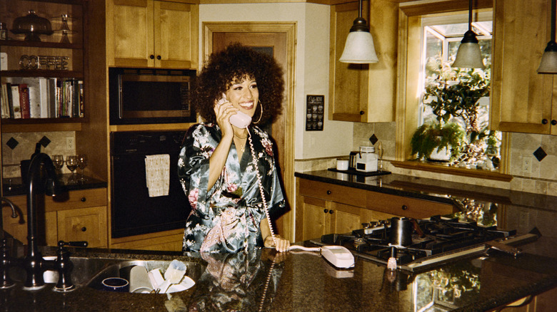A woman in a 1980s home talking on the phone