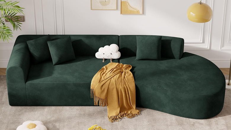 A curved sectional sofa in dark green corduroy