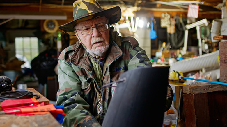 Man in camo clothing holding a coal scuttle out of focus from the camera