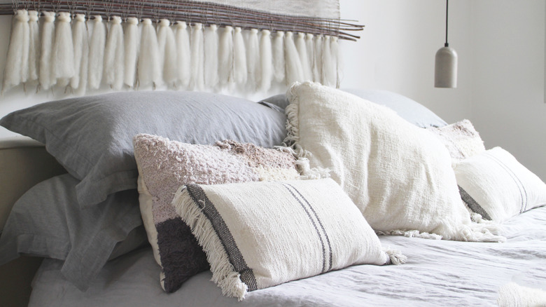 A pile of textured pillows on a neutral bed.