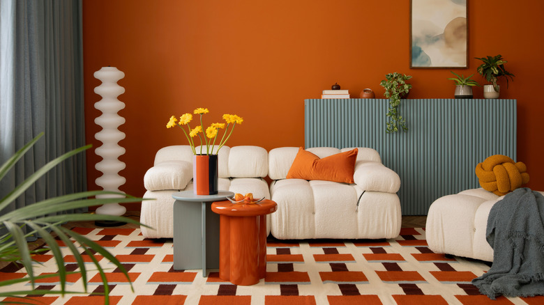 Contemporary colorful interior with modular sofa, warm orange tones, patterned rug, and minimalist furniture.