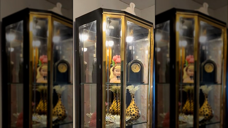 Brass curio cabinet with vintage decor pieces on shelves