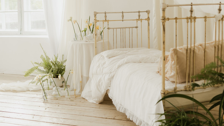 A brass bed frame made up with a white vintage bedspread.