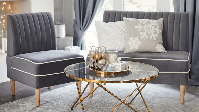 Polished brass glass coffee table in elegant sitting room with grey chairs