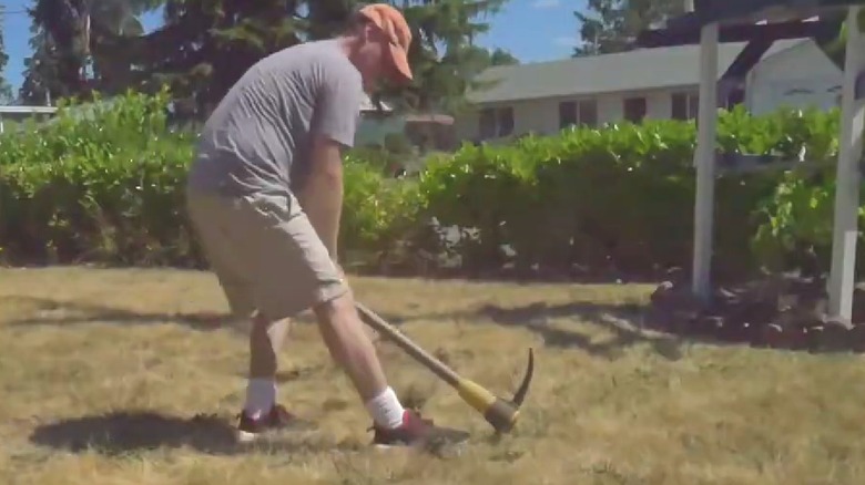 man digging weed with mattock