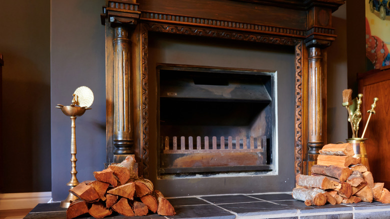 A fireplace with accessories such as fire pokers and piles of wood