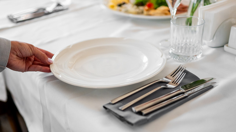 a person finishing a table setting
