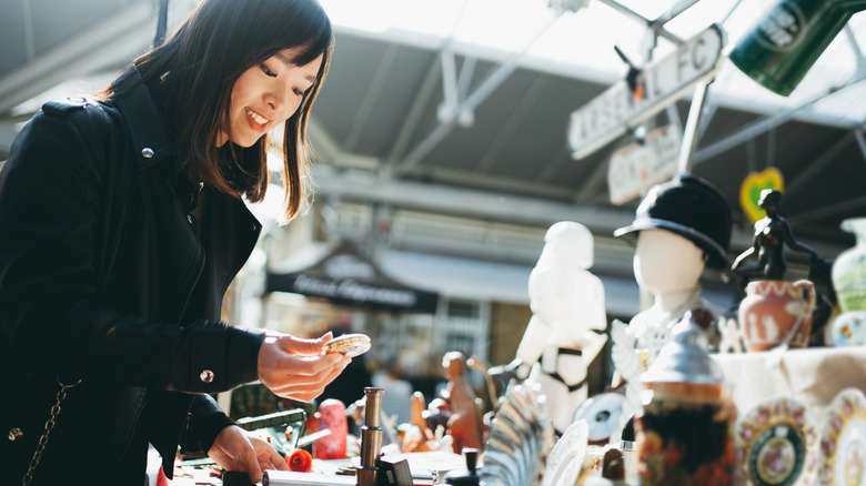 A woman looking at knickknacks on a flea market display table