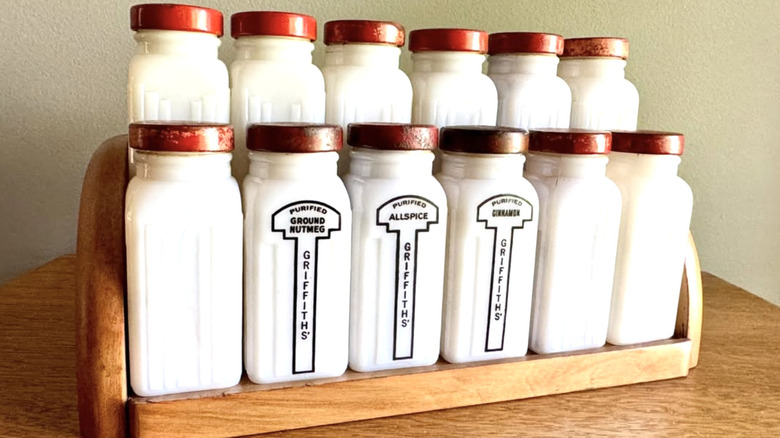 A set of early Griffith's spice jars with red lids on an original wood rack