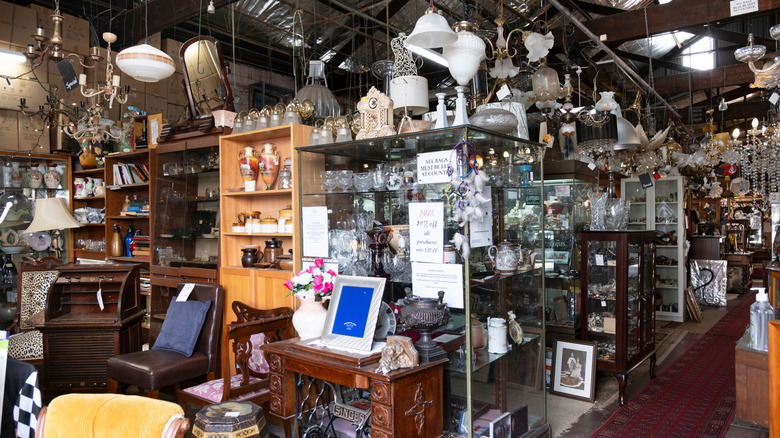A thrift store with lighting fixtures, glassware, and furniture on display.