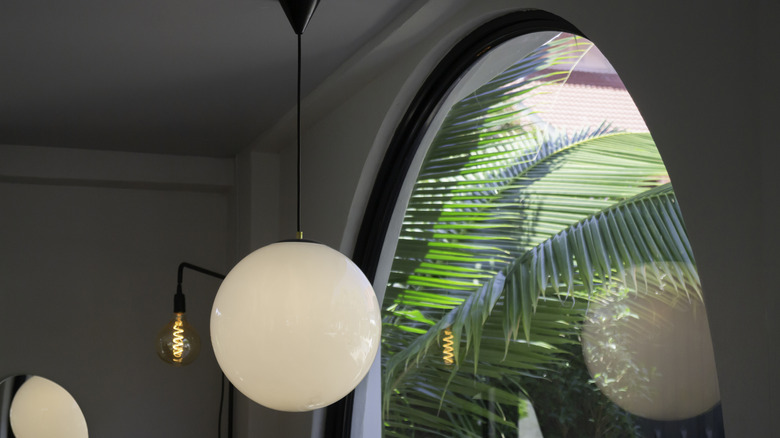 A globe pendant light in front of an arched window.