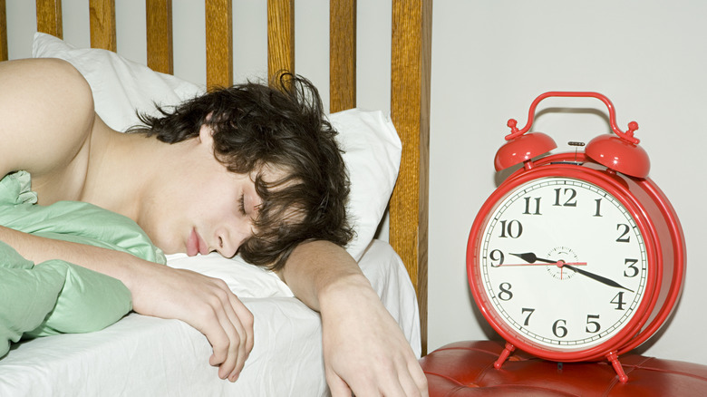 A man sleeping next to an alarm clock
