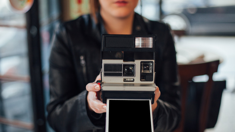A woman taking a photograph with a vintage Polaroid camera.