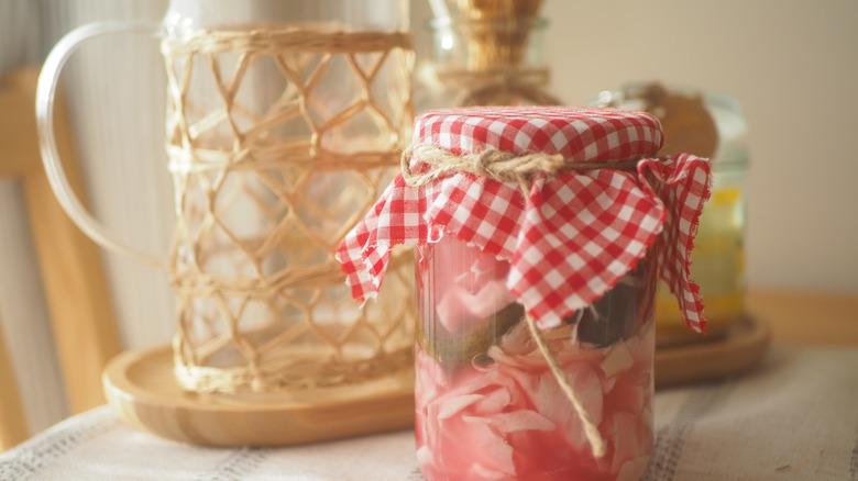 Homemade pickled vegetables in a jar on a table with red and white checked print