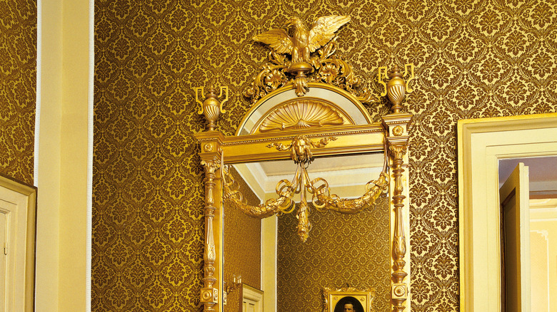 A gold rectangular mirror in a gold colored room.
