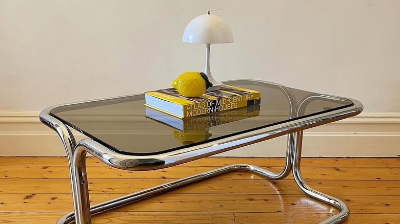 smoked glass and chrome coffee table with book and mushroom lamp displayed on tabletop