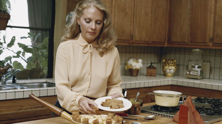 woman working in a kitchen in what looks to be the 1980s