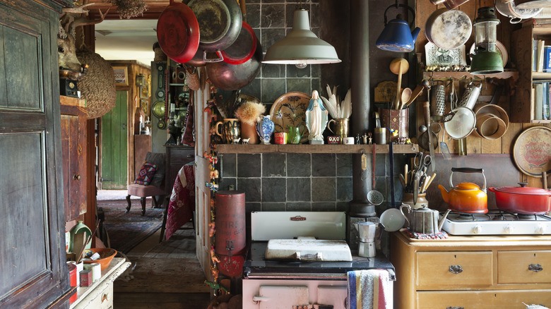 A quaint kitchen in a historic home with lots of tools and utensils hanging up or on shelves.
