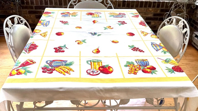 A vintage tablecloth with images of food and the names of spices printed along edges.