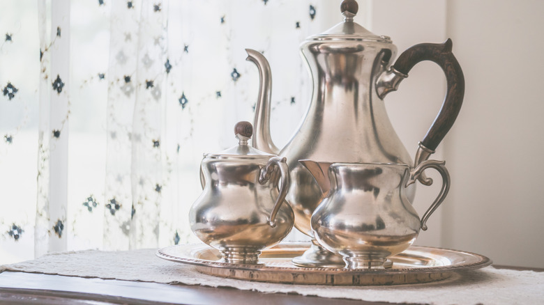 Silver teapot on a silver tray with silver sugar and creamer pots.