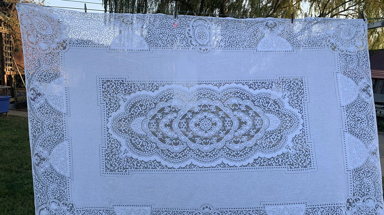 1980s polyester cotton lace tablecloth hanging on a clothesline outdoors