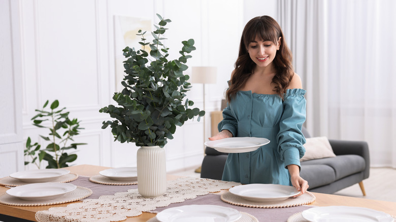 Woman setting table with plates in a bright room