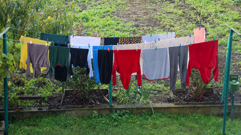 An outdoor clothesline with several colorful clothes.