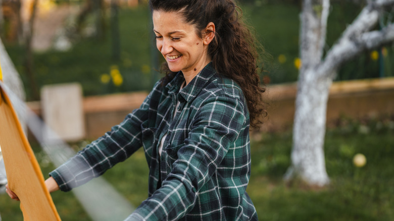 Woman holding something in her backyard with trees.