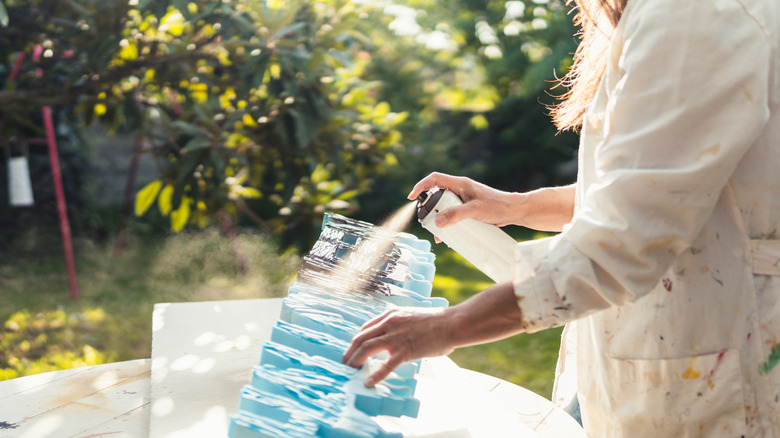 Woman spray painting a craft outside