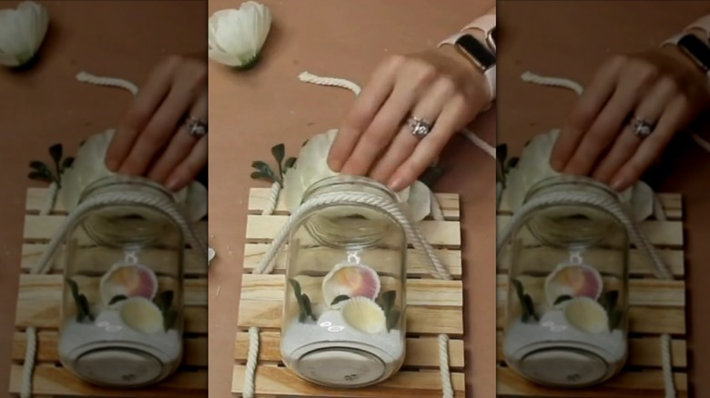 Crafter assembling mason jar on wooden pallets