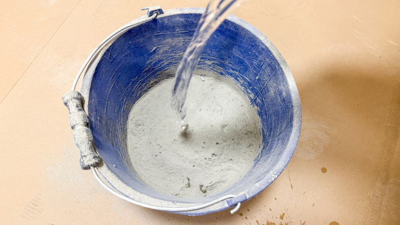 Pouring water into a cobalt bucket of quick setting cement.