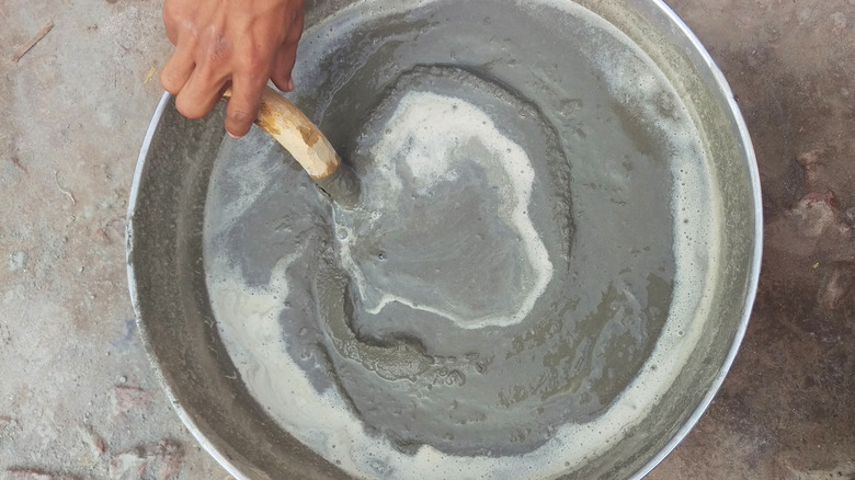 A person mixing a batch of quick-setting cement in a bowl