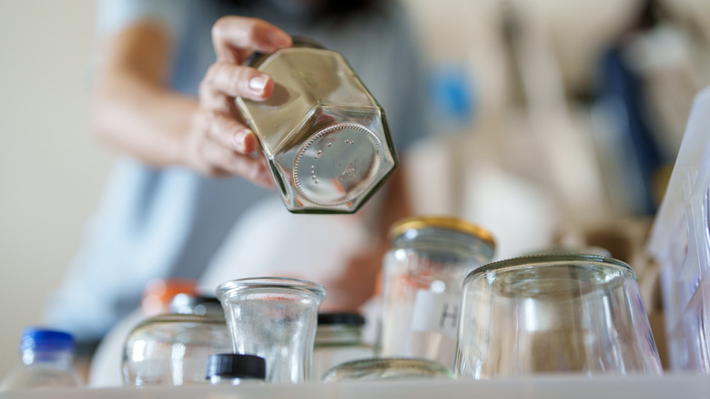 A person stowing away cleaned glass jars