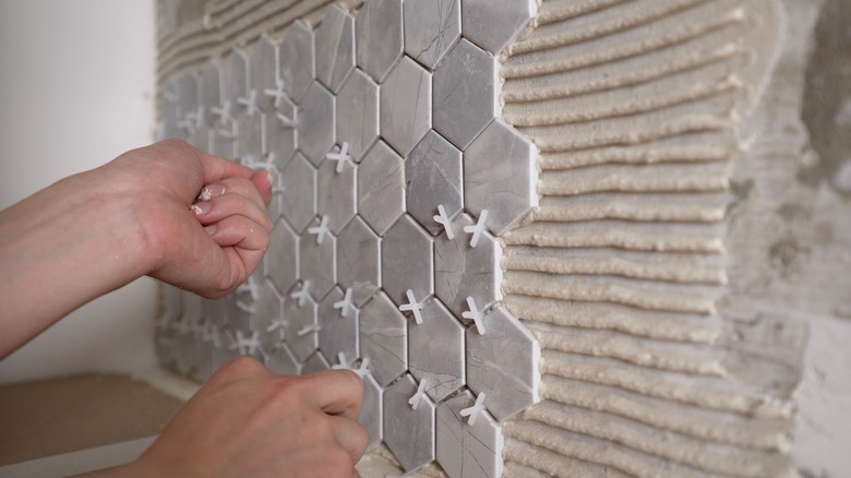 Hands placing tile