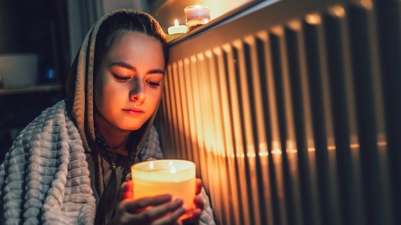 girl holding candle by radiator