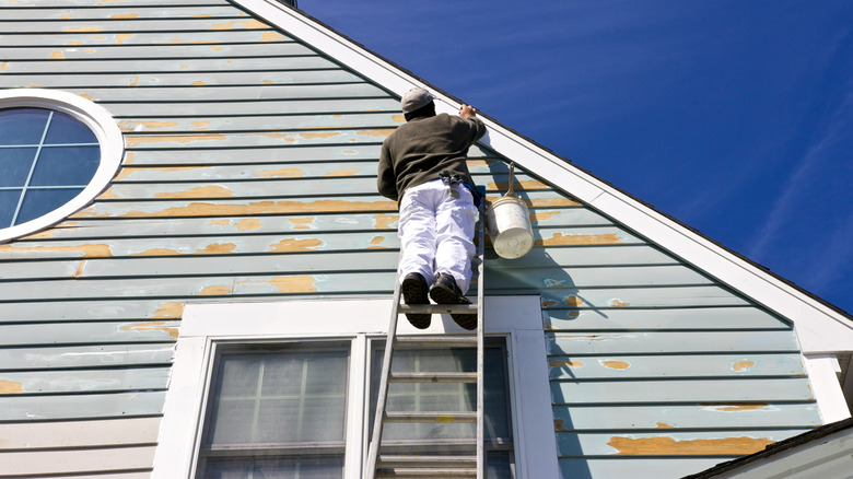 construction worker painting vinyl siding