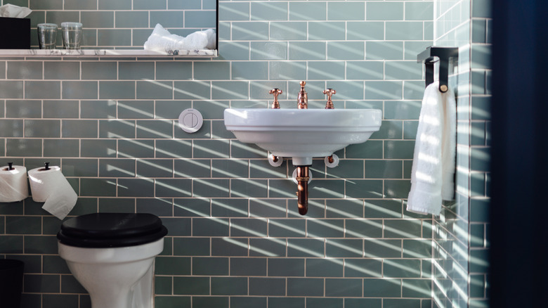 Bathroom with light blue green subway tiles.