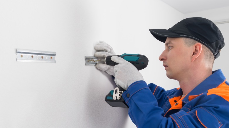 Worker drilling into drywall