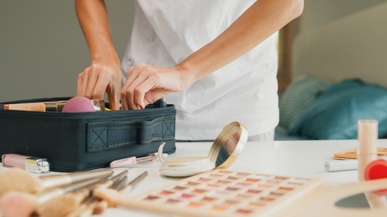 Person sorting through cosmetics in a black case