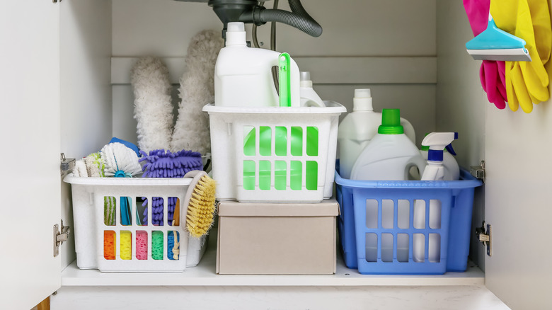 Cleaning supplies in bins under a sink