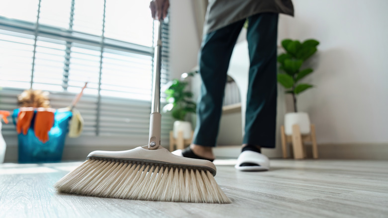 person sweeping wood floors with broom