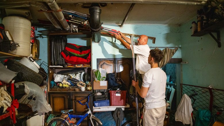 Two people check a garage for birds nests.