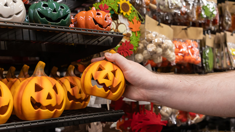 A person's hand reaching out and grabbing a cute pumpkin off a store shelf