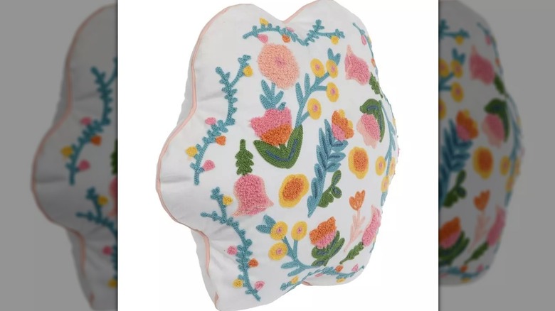 A white, flower-shaped pillow with colorful floral embroidery all over the front.