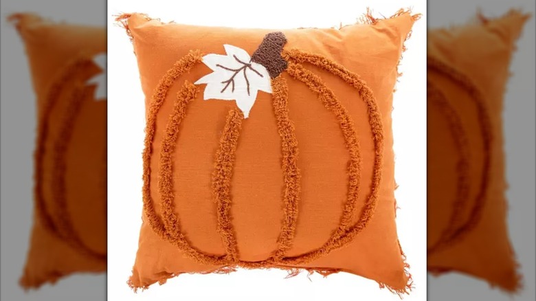 An orange pillow with a tufted pumpkin design.