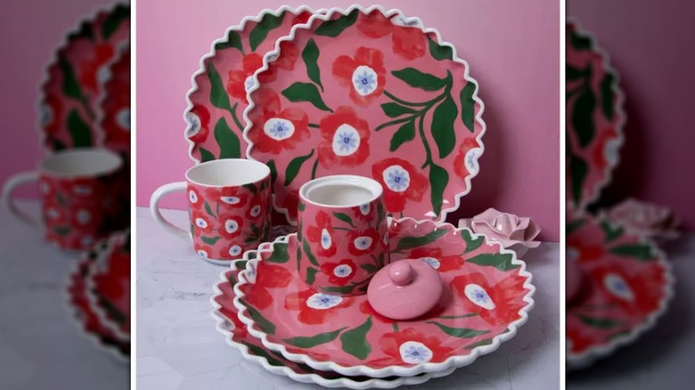 A poppy plate and cup set sits on a marble table with a pink wall behind them.