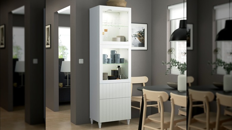 A white BESTÅ storage combination w/glass doors, full of cups and bowls of different shapes and sizes